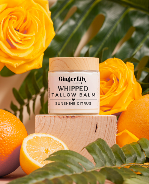 Ginger Lily whipped tallow balm jar with yellow roses and oranges on a wooden block