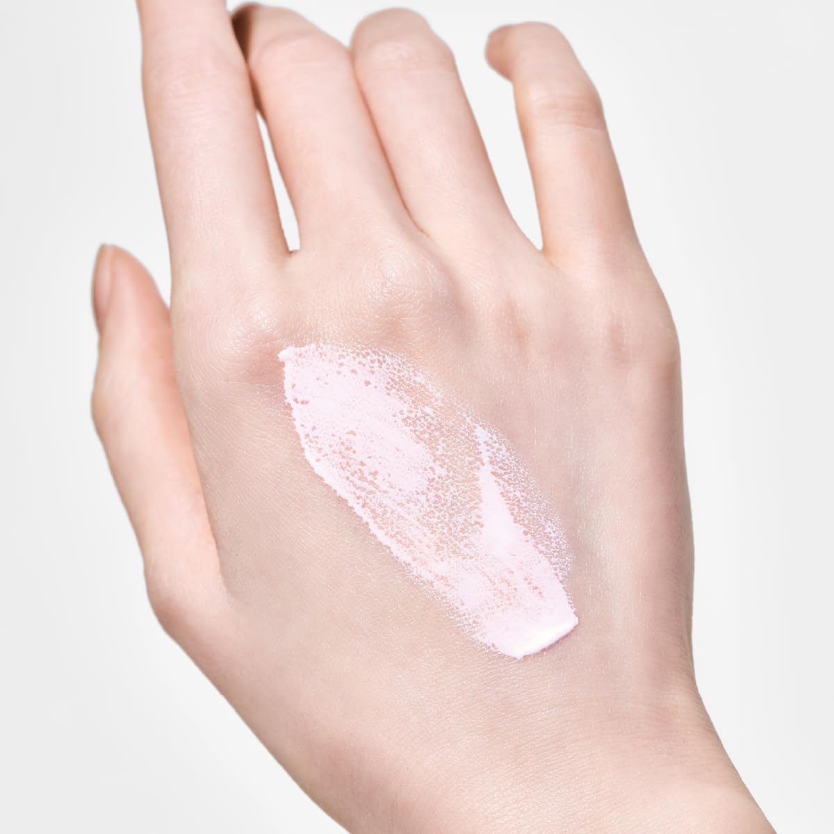 Hand with a small amount of white cream on the palm against a light background