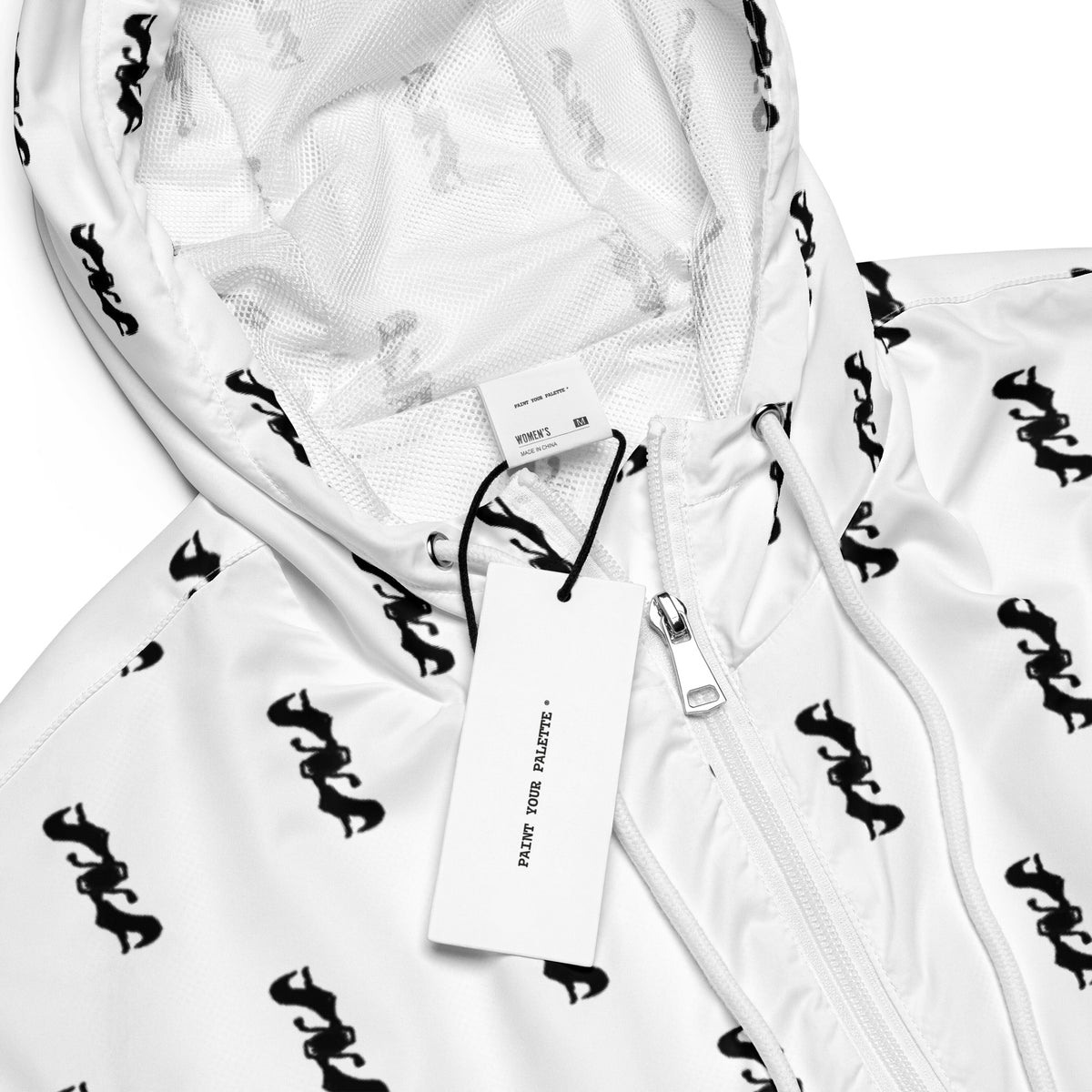 Close-up of a white hooded zip jacket with an allover black graphic print, a white zipper, and a hanging white product tag on a white background.