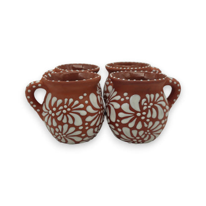 Four terracotta mugs with floral patterns on a white background