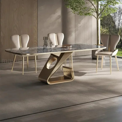 Modern dining table with marble top and unique base design in a room with large windows.
