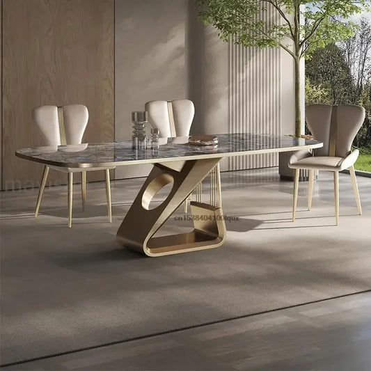Modern dining table with marble top and unique base design in a room with large windows.