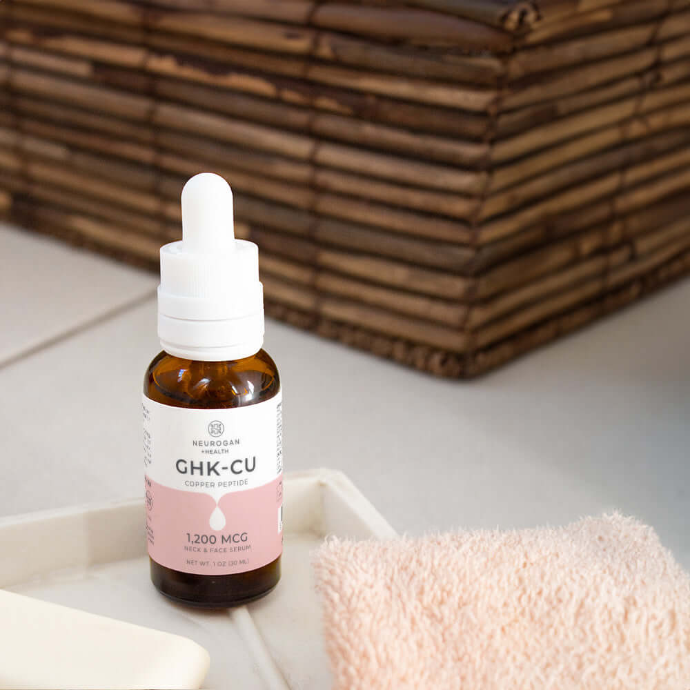 Bottle of GHK-CU serum with dropper on a white surface with towels in the background