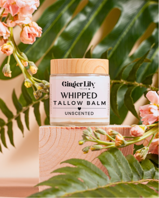 Ginger Lily whipped tallow balm jar with flowers and leaves in the background