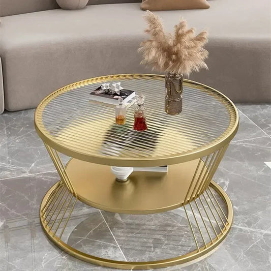 Round gold coffee table with a glass top in a living room setting.
