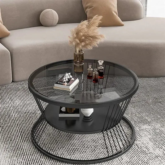 Round black metal coffee table with a glass top in a living room setting.