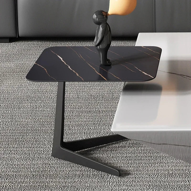 Modern black marble side table with a decorative figure on a gray carpeted floor.