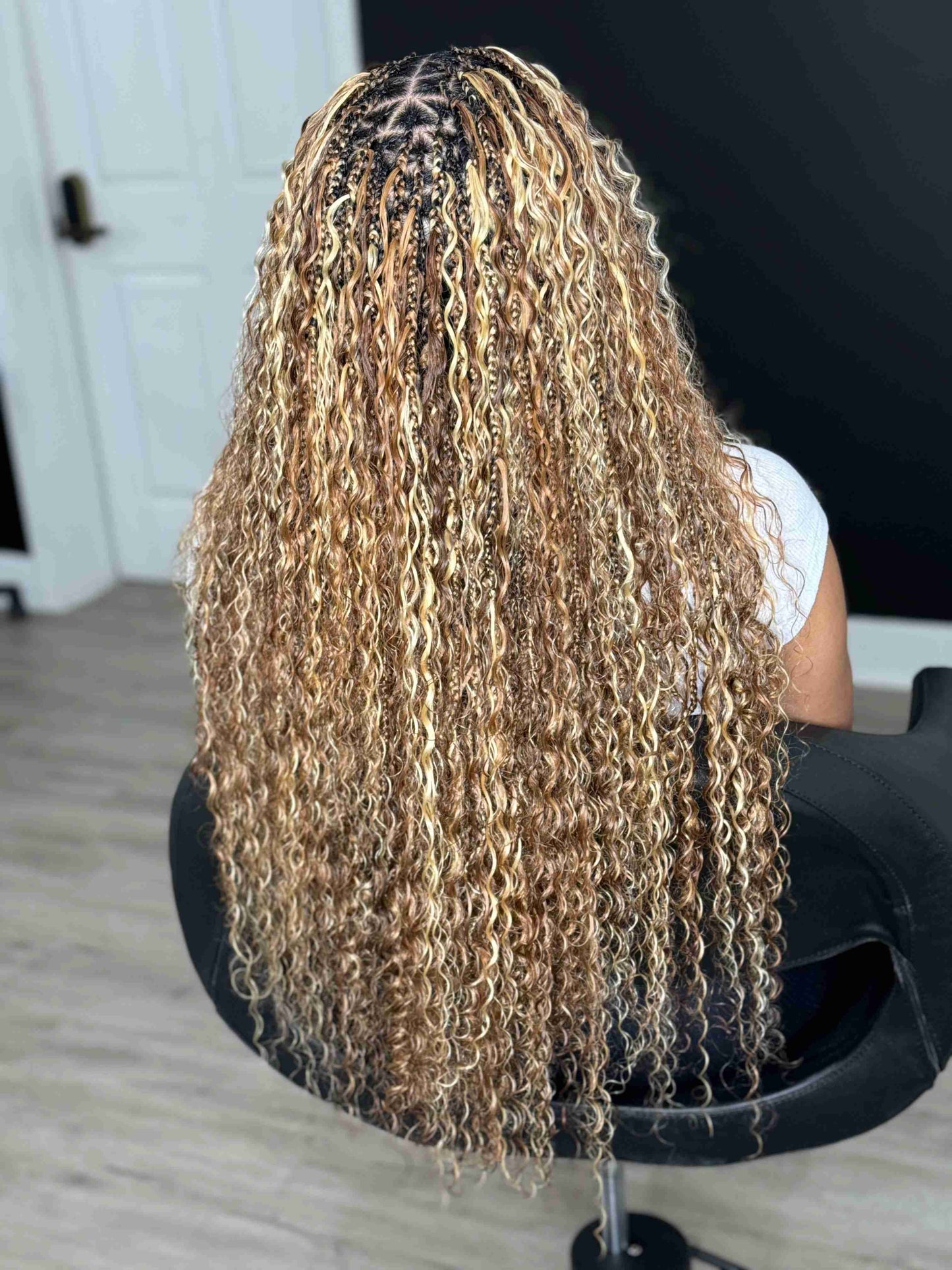 Person with long, wavy hair sitting in a chair indoors.