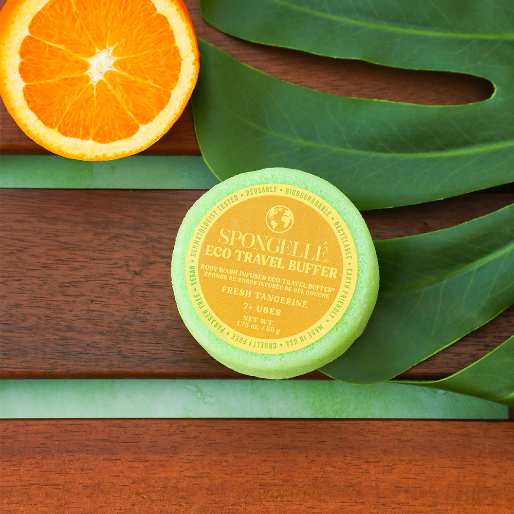 Spongellé Eco Travel Buffer on a wooden surface with an orange and leaves