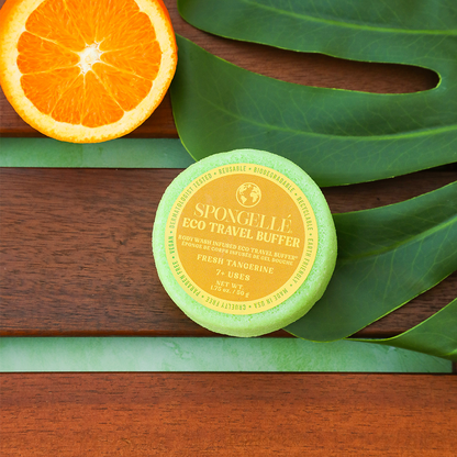 Spongellé Eco Travel Buffer on a wooden surface with an orange and leaves