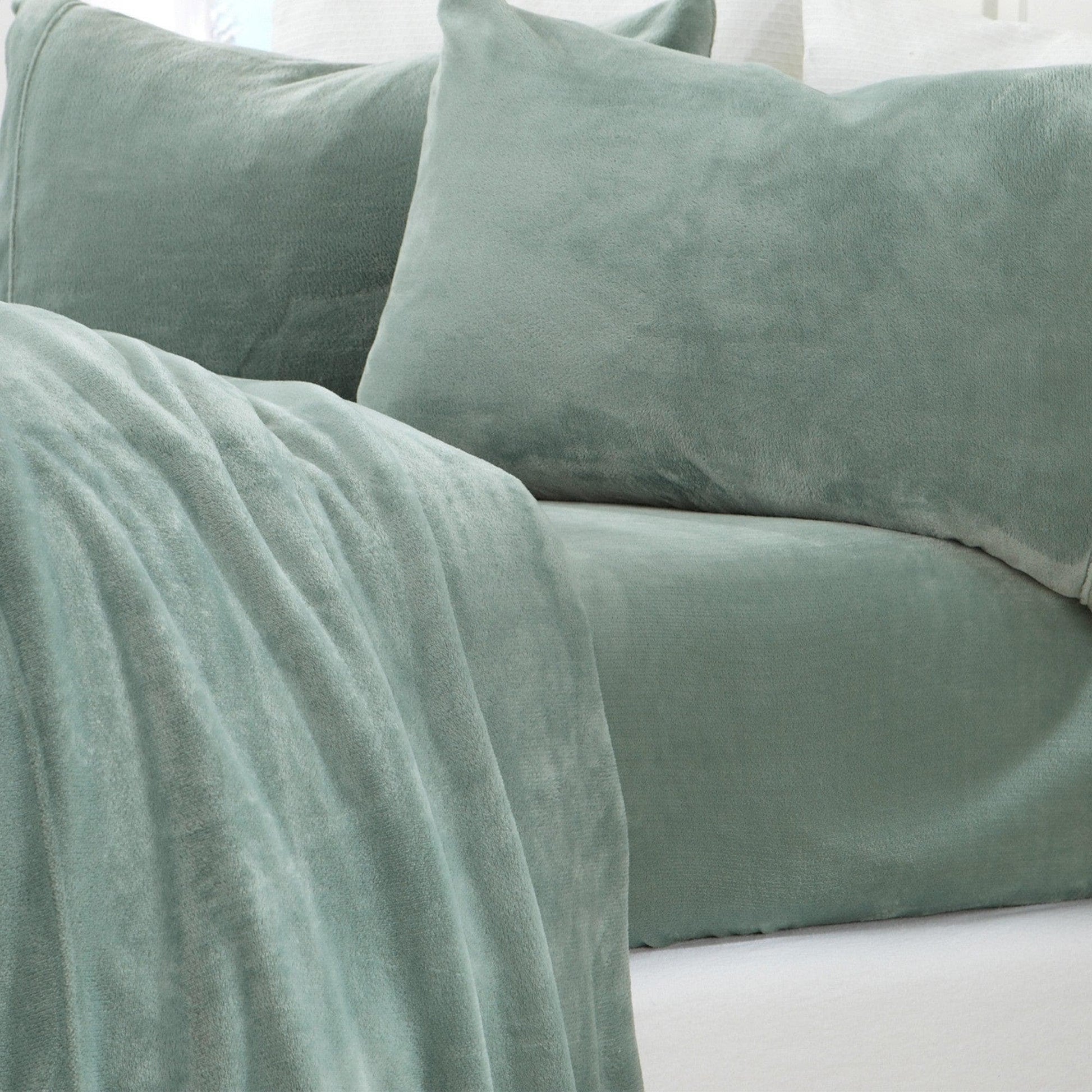 Green velvet pillows and blanket on a white surface