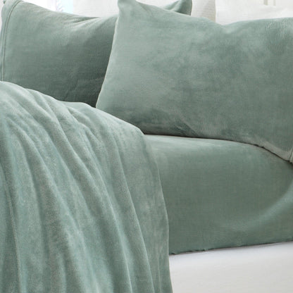 Green velvet pillows and blanket on a white surface