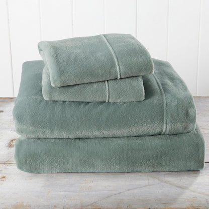 Set of green towels stacked on a wooden surface with a white wooden panel background