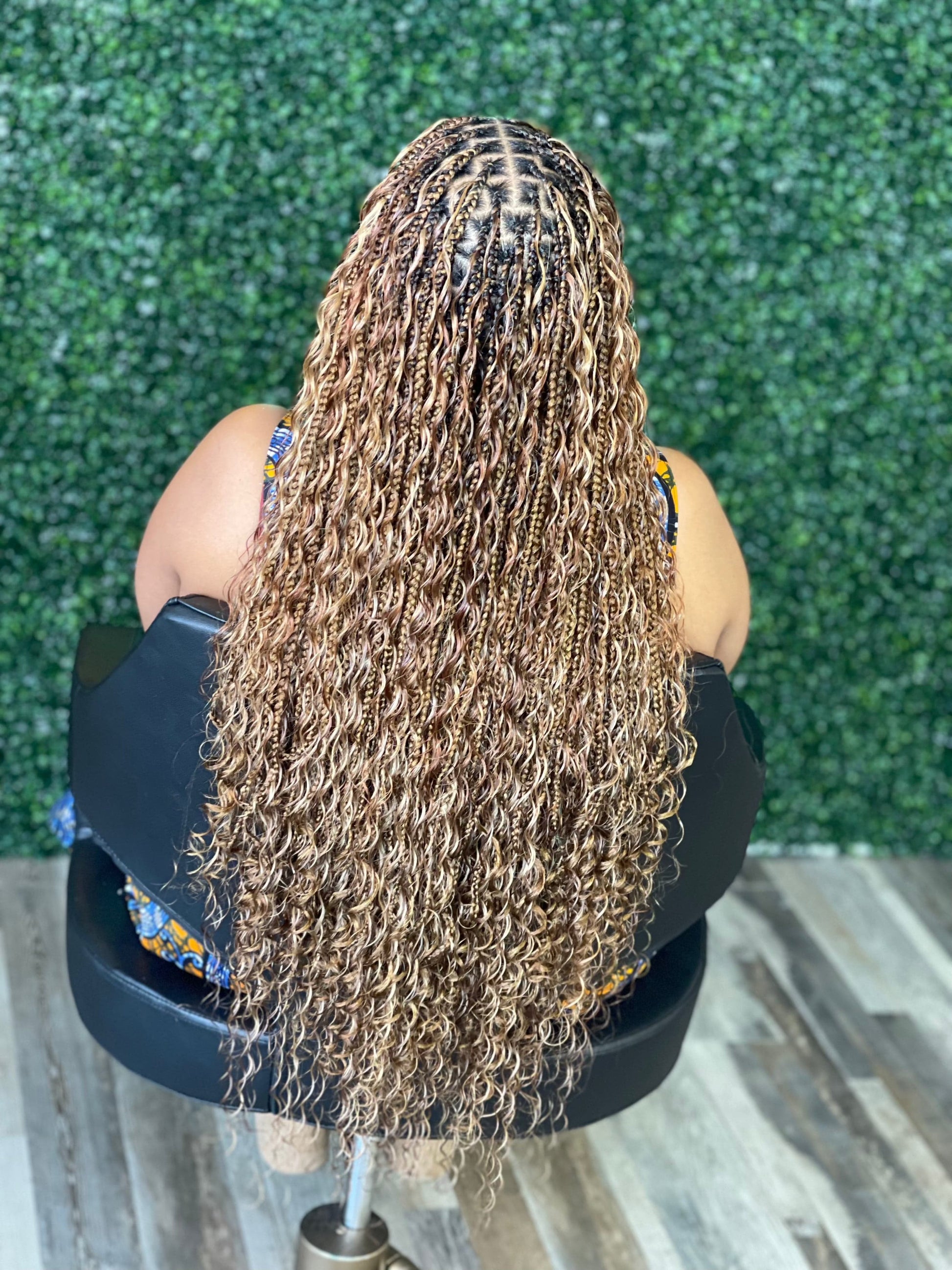 Person with braided hair sitting on a chair against a green artificial grass background