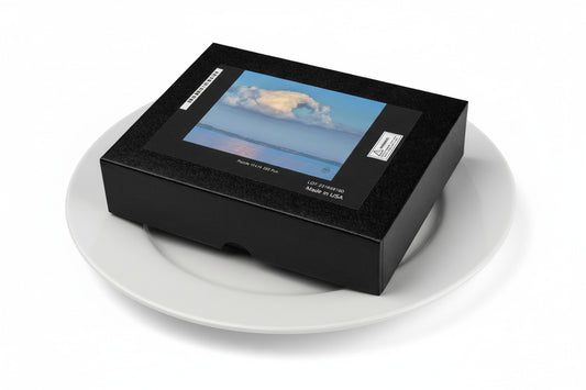 Your Suggested Brand Jigsaw Puzzle Box displaying an image of a cloud over water on a dinner plate. Serving size 1 puzzle and it's calorie free.