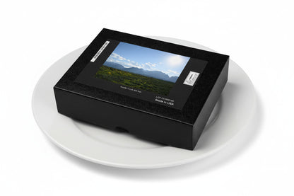 Your Suggested Brand jigsaw puzzle box on a plate with a scenic landscape cover on a white background, on a dinner plate.