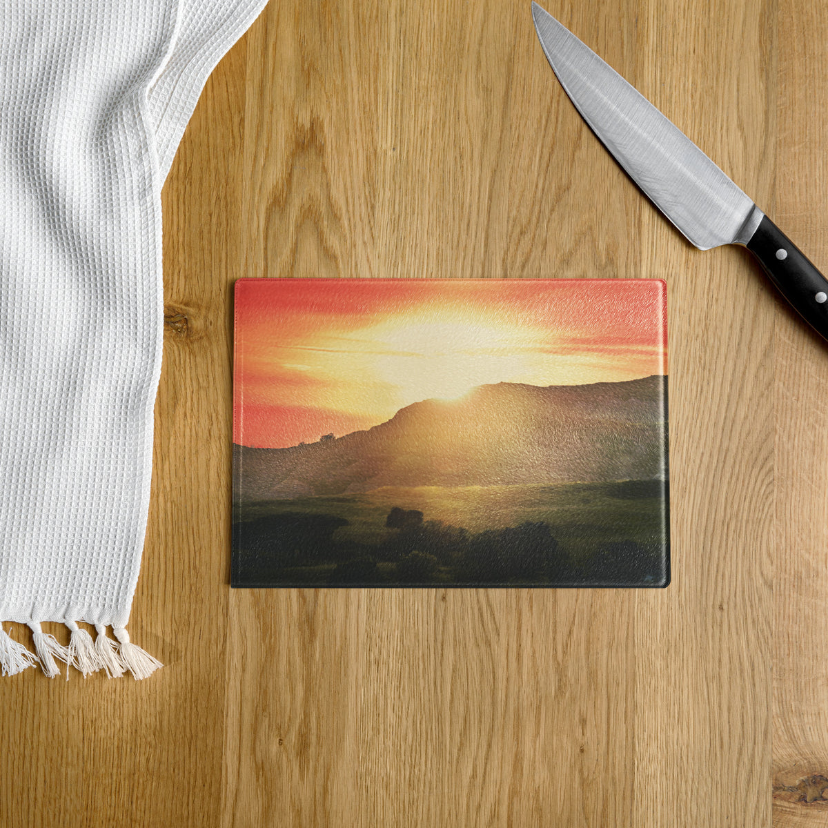 Cutting board with sunset design on a wooden surface 
